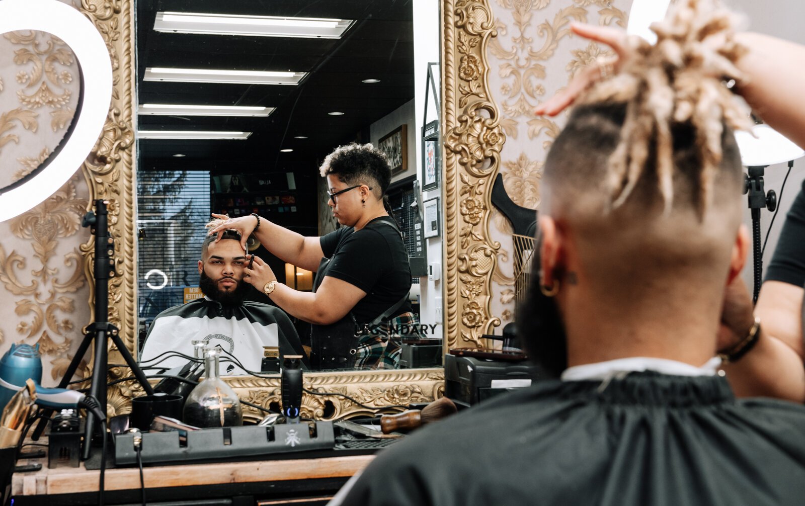 Sasha Chaney, Master Barber and Owner of Legendary Barber Lounge works on giving fellow barber Marcus Chezem a high ball fade with a beard edge up.