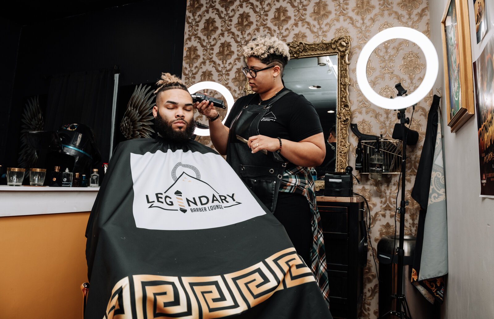 Sasha Chaney, Master Barber and Owner of Legendary Barber Lounge works on giving fellow barber Marcus Chezem a high ball fade with a beard edge up.