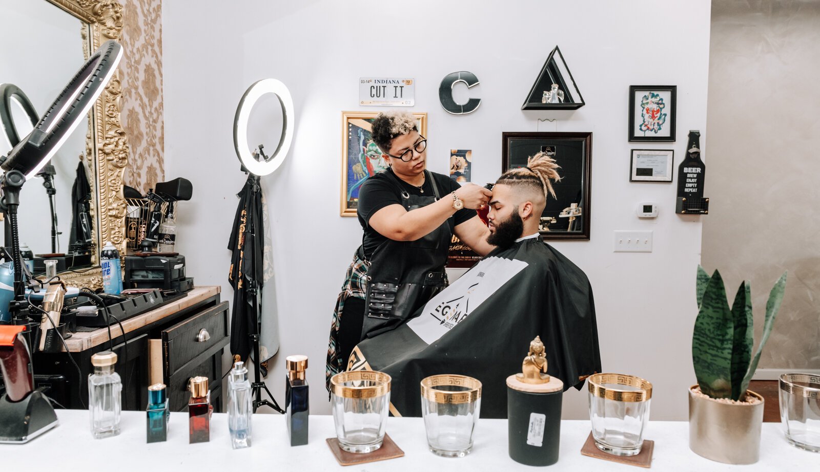 Sasha Chaney, Master Barber and Owner of Legendary Barber Lounge works on giving fellow barber Marcus Chezem a high ball fade with a beard edge up.