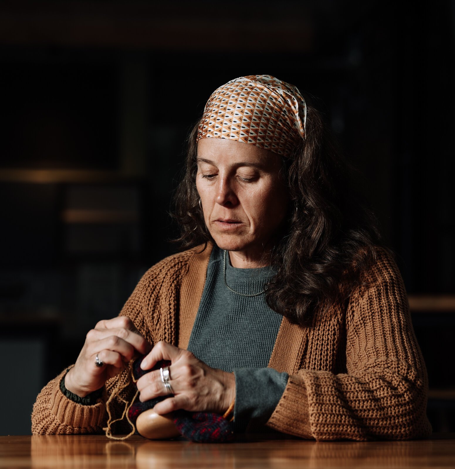 Megan Burton, owner of K1nd Goods, works on mending a sock at Electric Works in the West Hall.