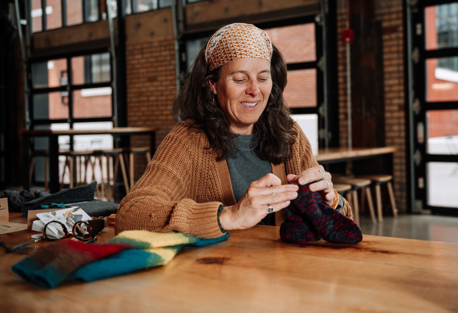 Megan Burton, owner of K1nd Goods, works on mending a sock