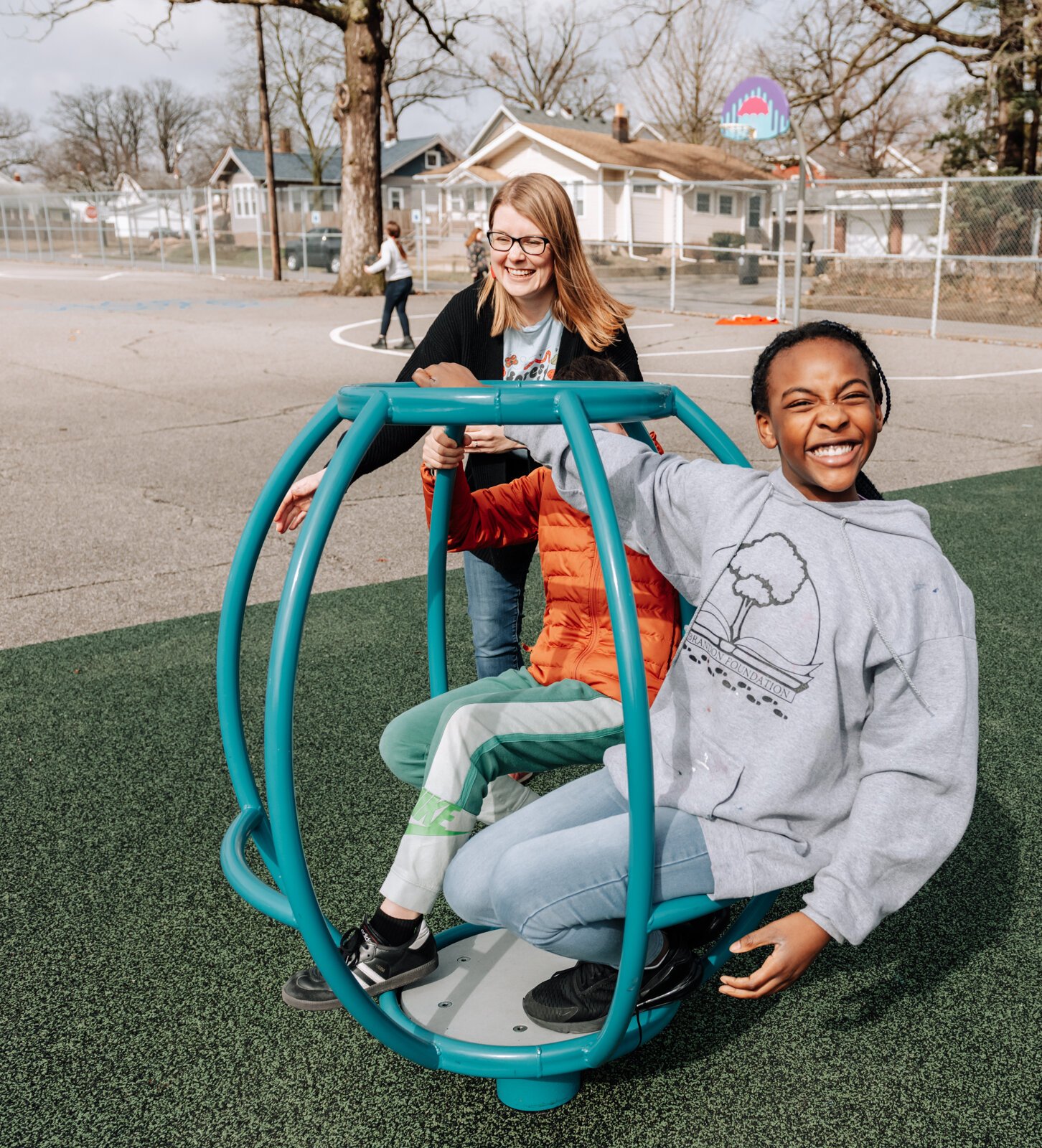 Leitia McHugh helps students Kaniyah Lacey and Spencer McComas on the Comet Spinner during the fourth grade recess at Forest Park Elementary School.