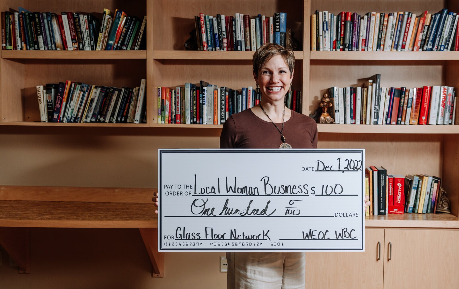 Leslee Hill, Program Director at WEOC Women's Business Center shows an example of a donor check for local women business at the Northeast Indiana Innovation Center.