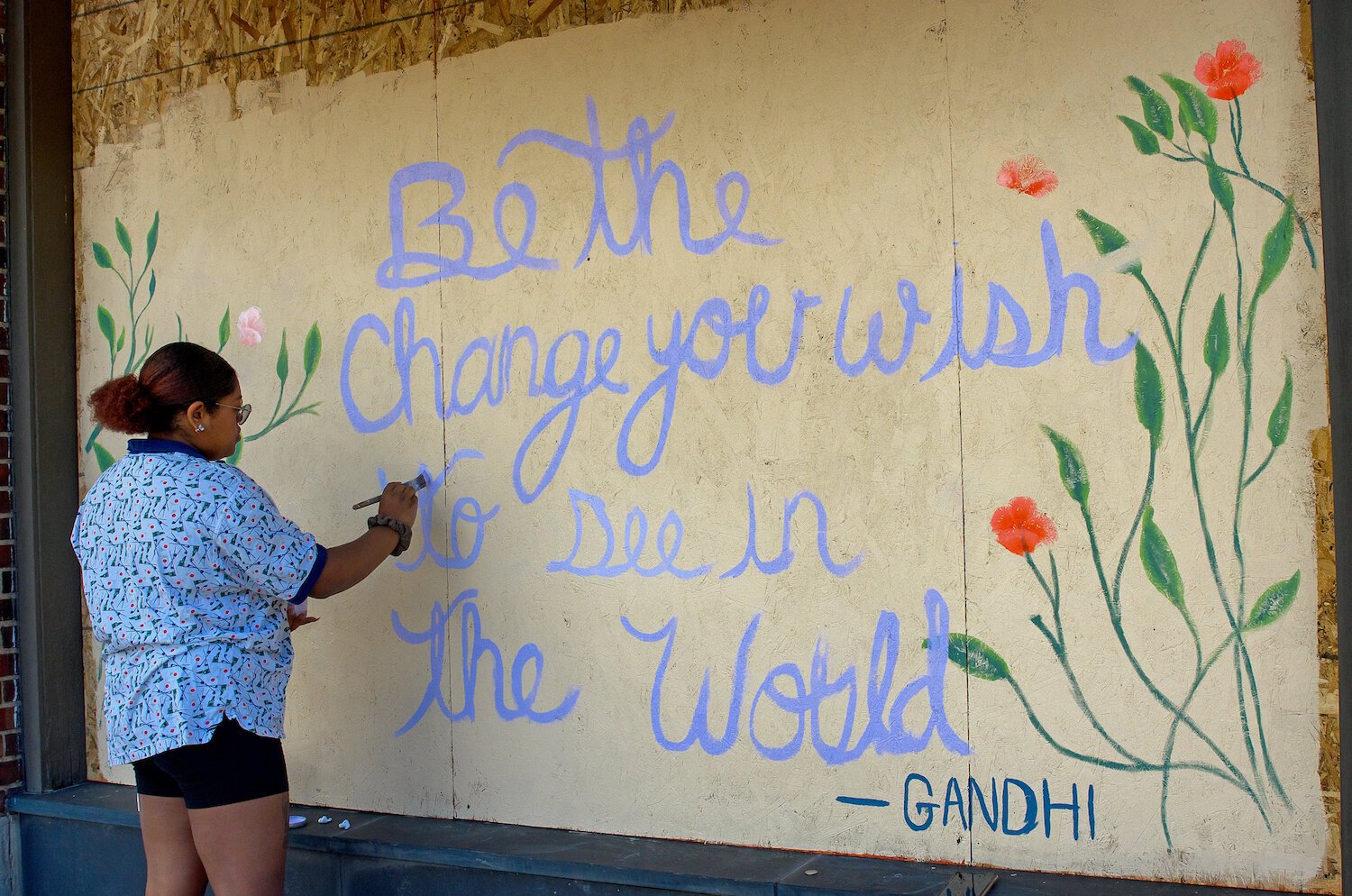 Isis Shaw paints a mural on Visit Fort Wayne's windows in downtown Fort Wayne.