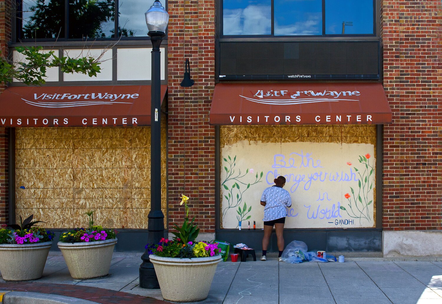 Isis Shaw paints a mural on Visit Fort Wayne's windows in downtown Fort Wayne.