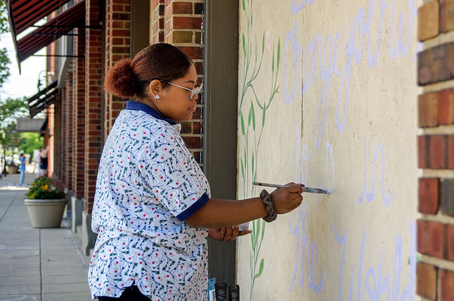 Isis Shaw paints a mural on Visit Fort Wayne's windows in downtown Fort Wayne.