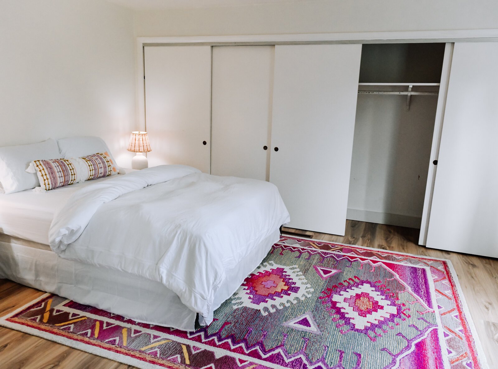 One of the bedrooms features tons of storage and a pop of color with a pink rug.