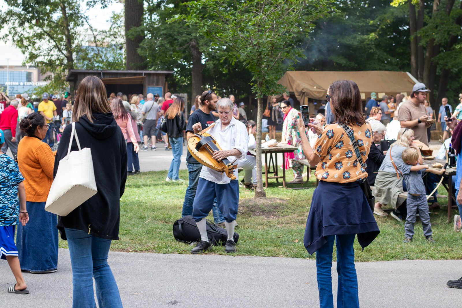 Passing by, people stop to record a musican performing.