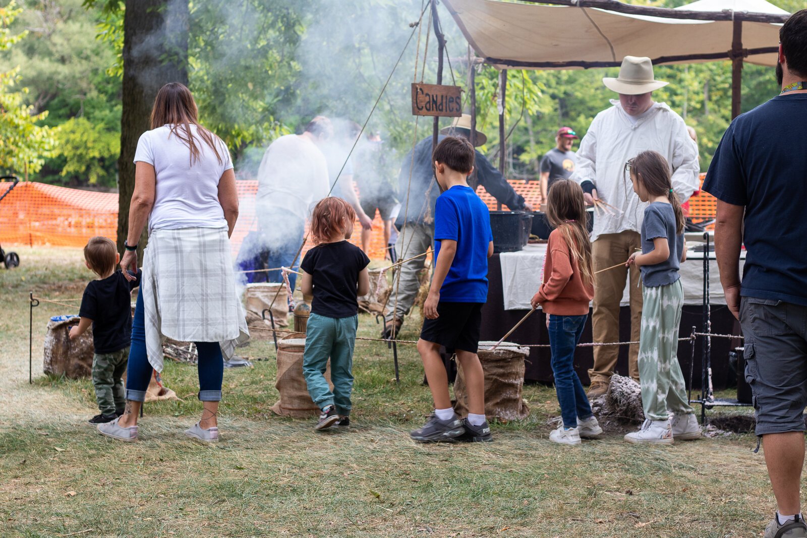 Festival attendees at a candle-making booth walk around in a circle, dipping their soon-to-be candles in wax and water repeatedly.