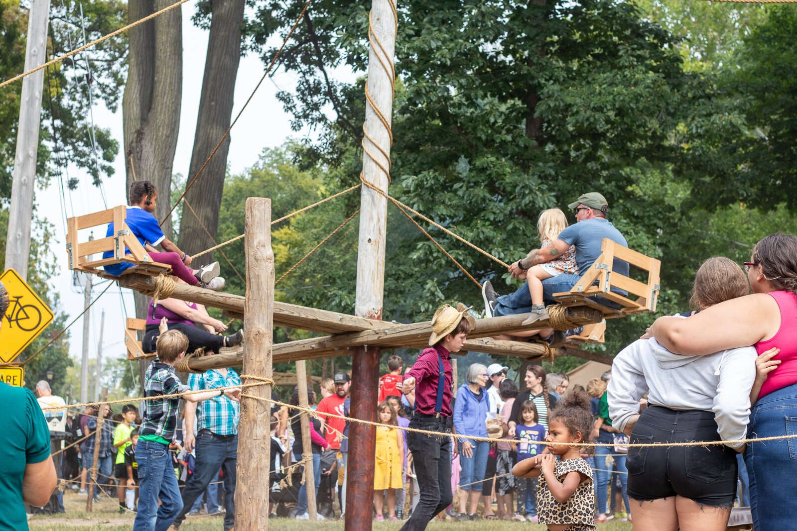 Children and their parents prepare to go for a ride on a homemade swing.