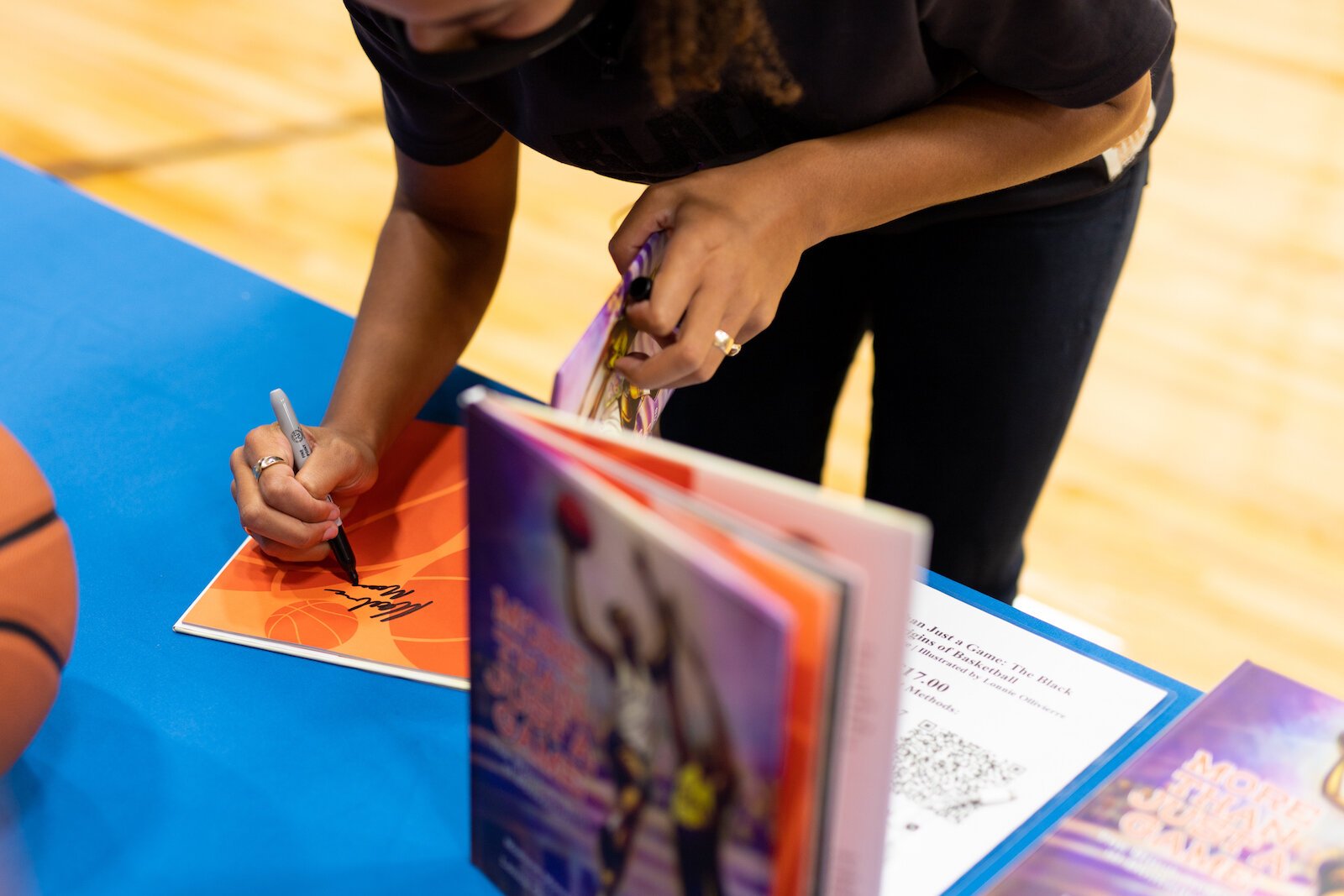 Madison Moore, a Fort Wayne-raised author of "More Than Just a Game: The Black Origins of Basketball," signs copies of her book at the Fort Wayne Boys & Girls Club.