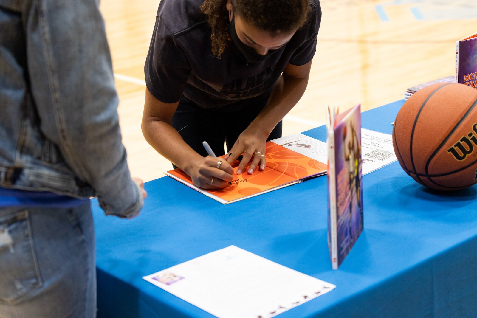 Madison Moore, a Fort Wayne-raised author of "More Than Just a Game: The Black Origins of Basketball," signs copies of her book at the Fort Wayne Boys & Girls Club.