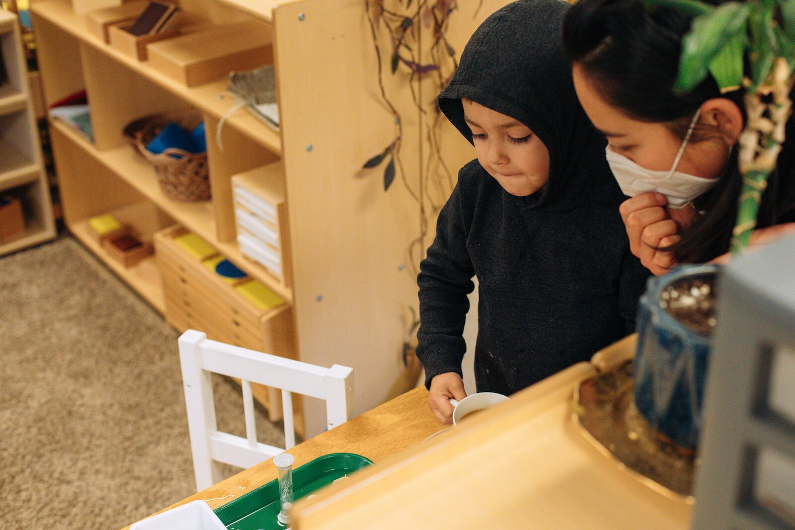 A guide (teacher), works with a child on classroom activities.