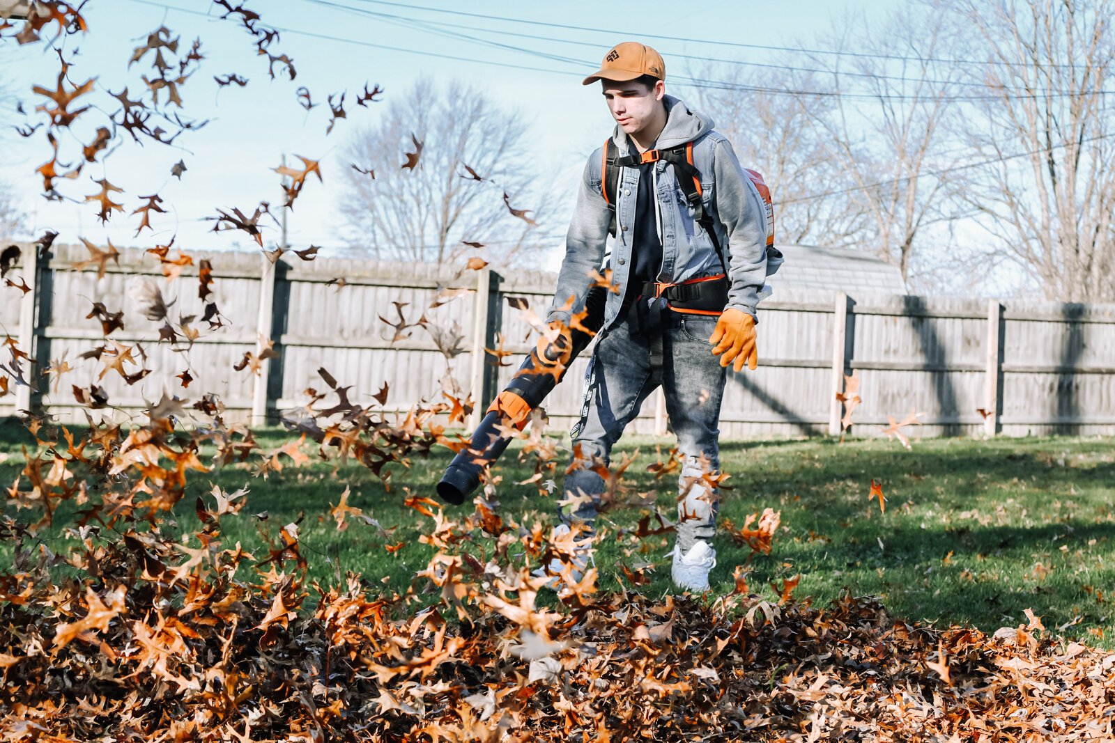 A volunteer with NeighborLink, Elijah Wood, 17, helps clear leaves with a leaf blower at a home in Fort Wayne.