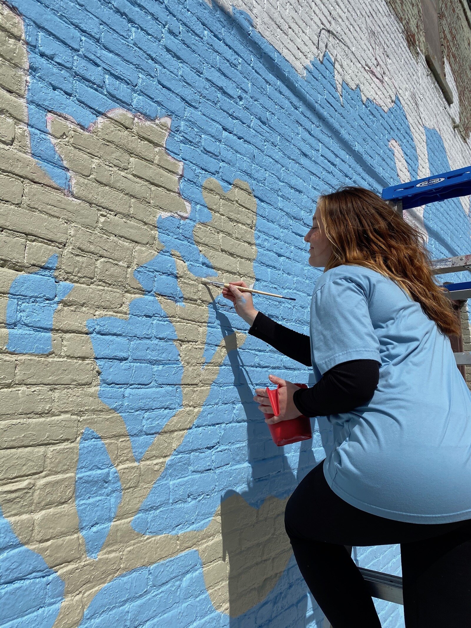 USF’s Mural Painting and Public Art Class works on a mural in downtown Fort Wayne at 1217 Broadway.
