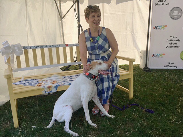 Patti Hays tries out a Buddy Bench donated to Fairfield Elementary School, painted by Vicki Junk Wright.