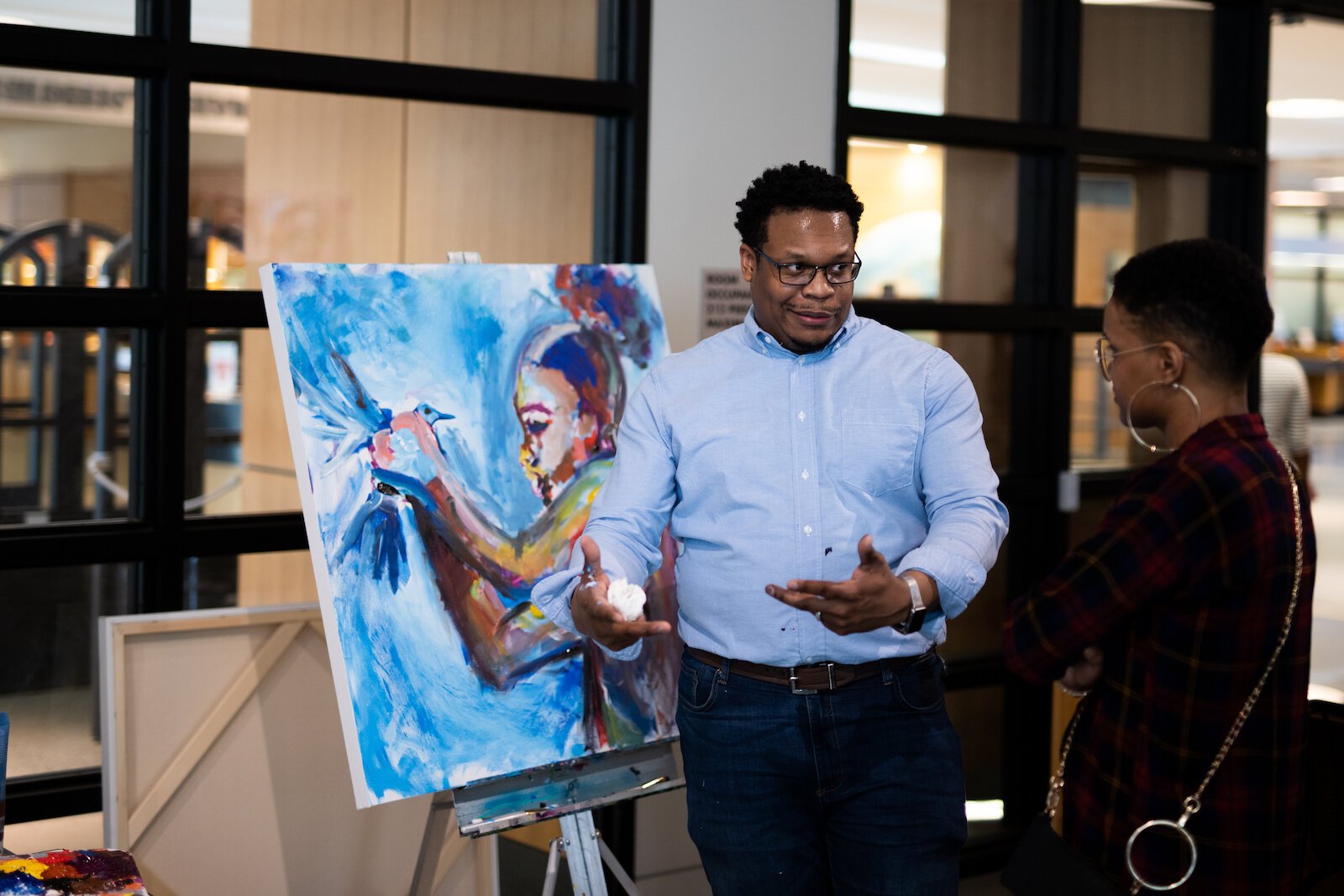 Artist Theopolis Smith III speaks about his painting to an attendee at the gallery.