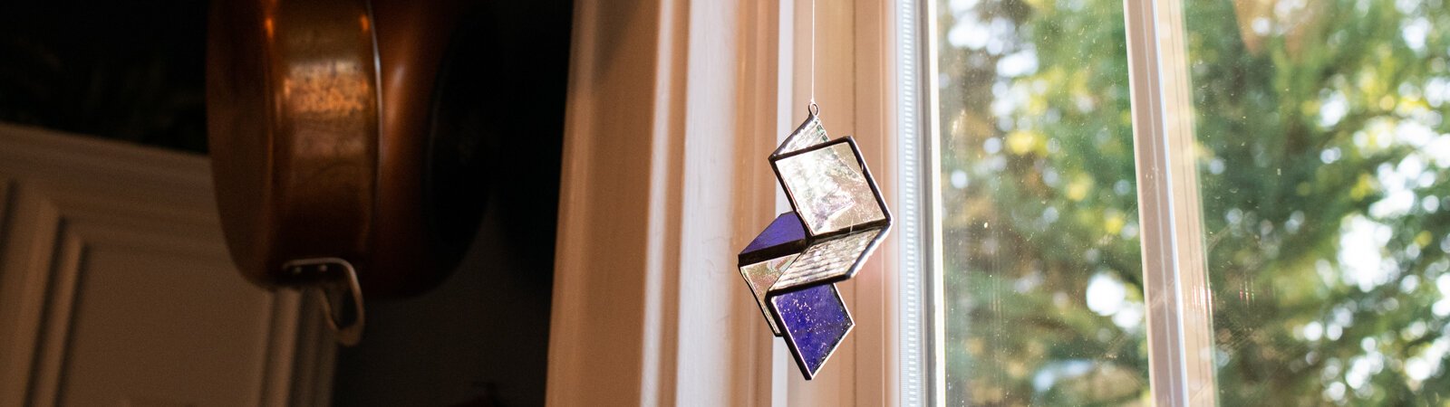 A stained-glass suncatcher made by Kevin Christon of Fort Wayne hangs from the kitchen window in his home.