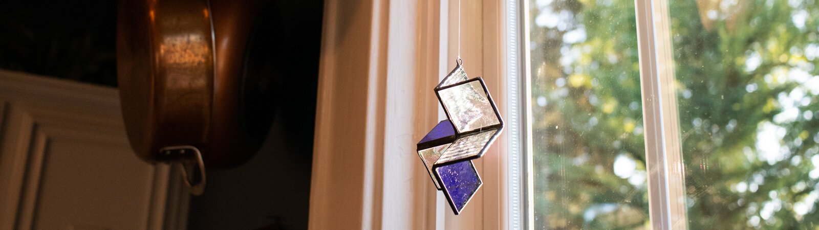 A stained-glass suncatcher made by Kevin Christon of Fort Wayne hangs from the kitchen window in his home.