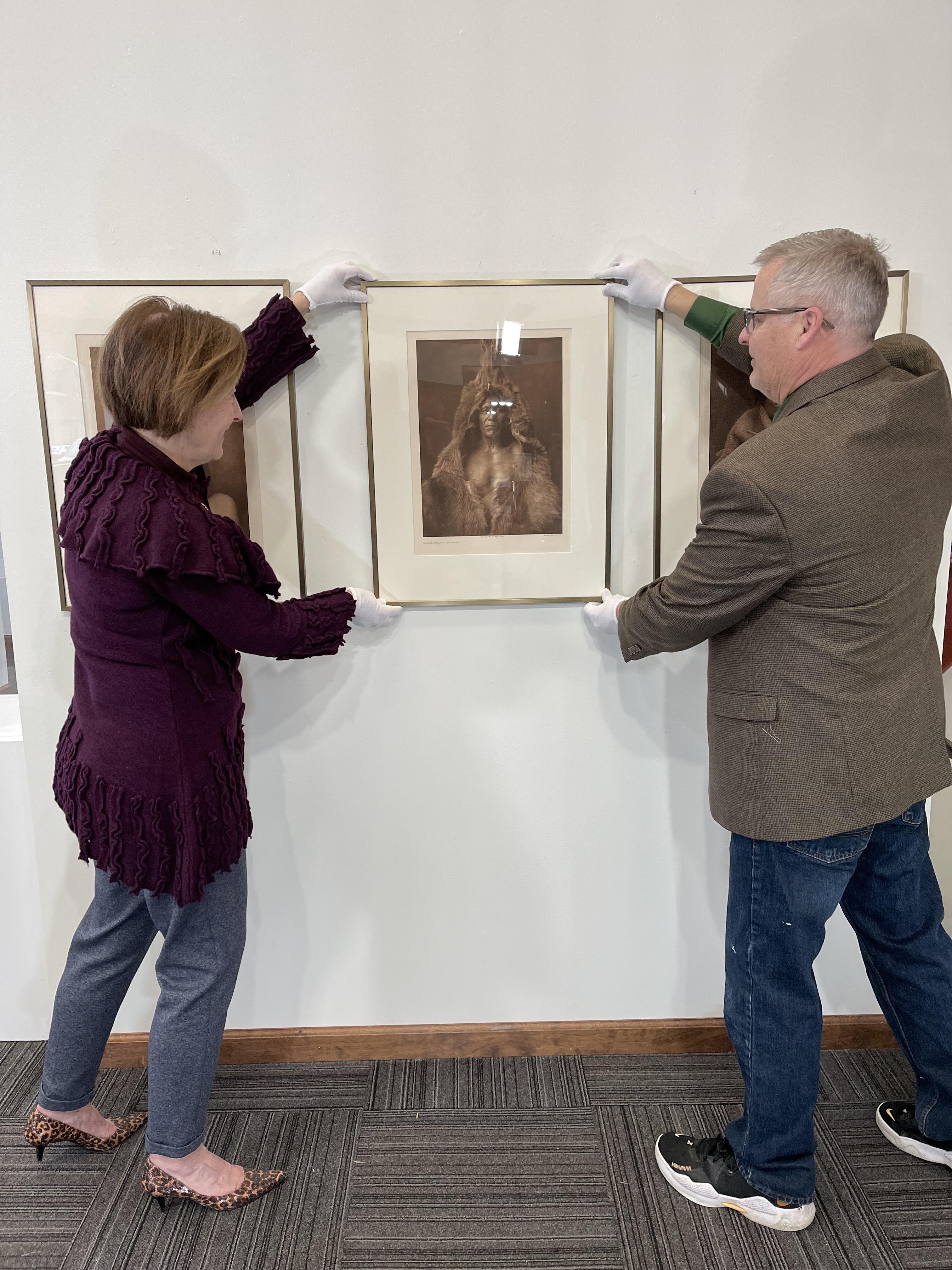 Gallery Coordinator and Curator Angela Green and Museum Director Jim Gabbard install a piece by Edward Curtis.
