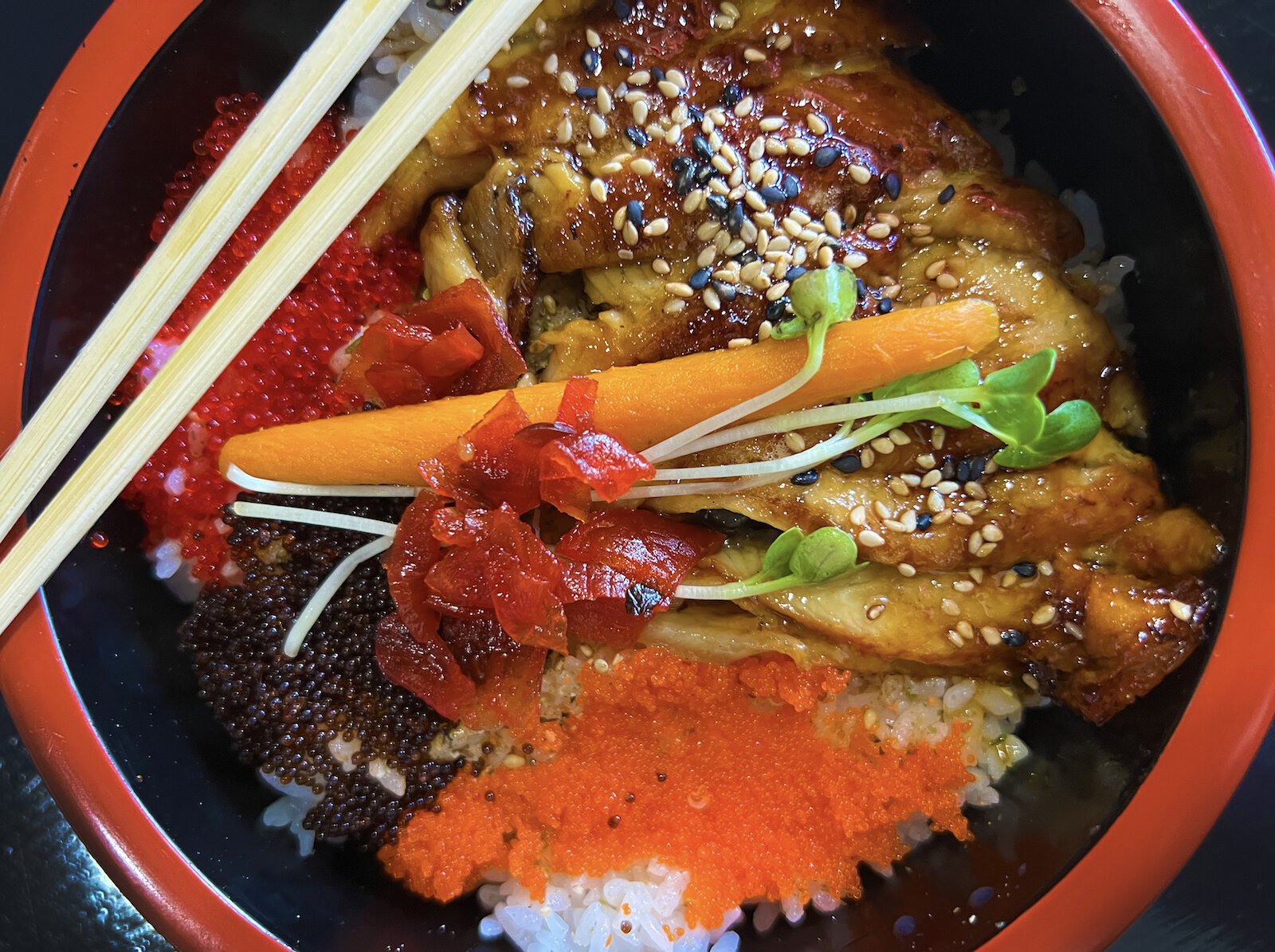 The unagi donburi is presented beautifully with colorful sections of eel, tobiko, and masago placed over subtly seasoned rice.