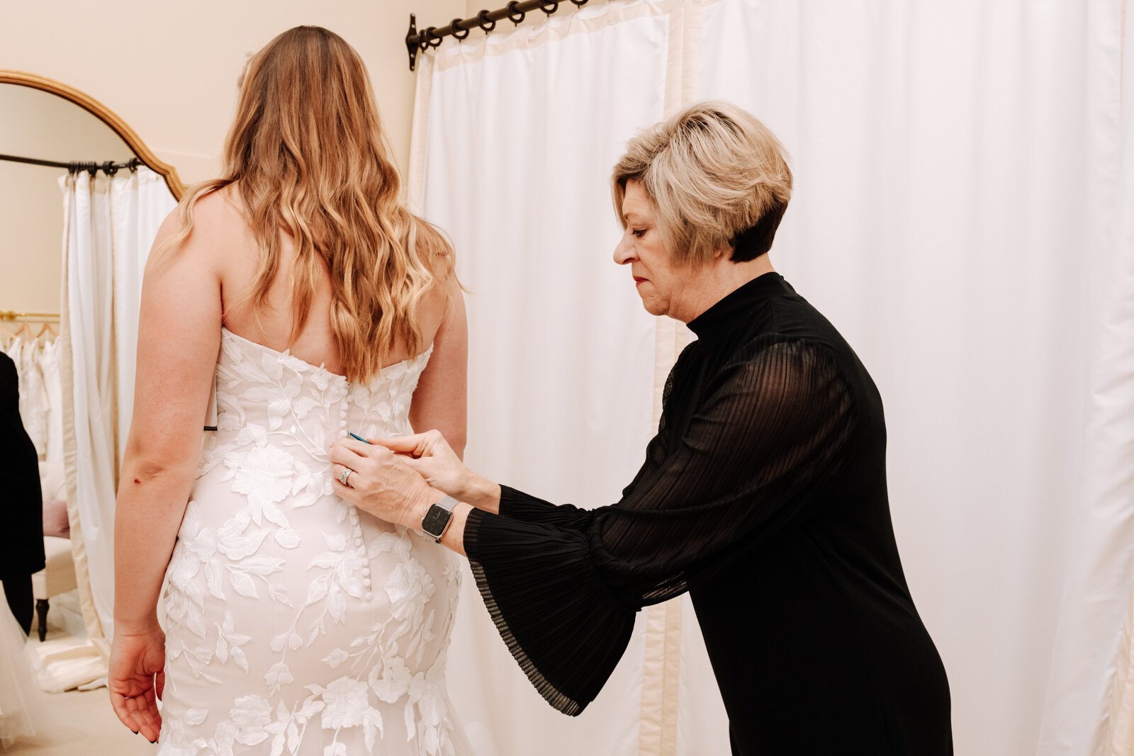 Lisa Downs, owner of Ellen's Bridal & Dress Boutique, helps customer Bailey Lundmark with a dress she is trying on 