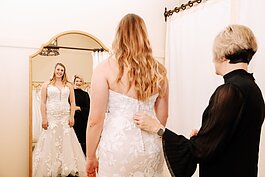 Lisa Downs, owner of Ellen's Bridal & Dress Boutique, helps customer Bailey Lundmark with a dress she is trying on 