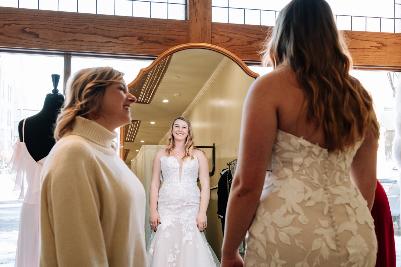 Bride Bailey Lundmark talks with her mother Missy Hartley while trying on a dress in front of The Yes Wall at  Ellen's Bridal & Dress Boutique.