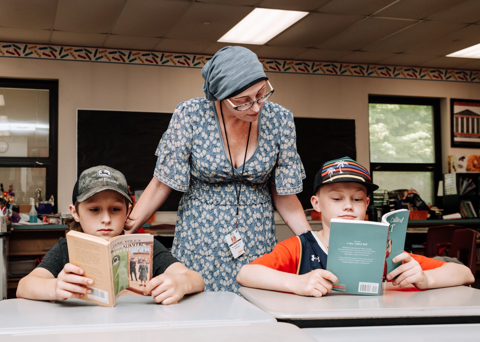 Keri Mertz helps students Jaydenn Mertz (her son), left, and Camden McKee with their books in her classroom at O J Neighbours Elementary School in Wabash.