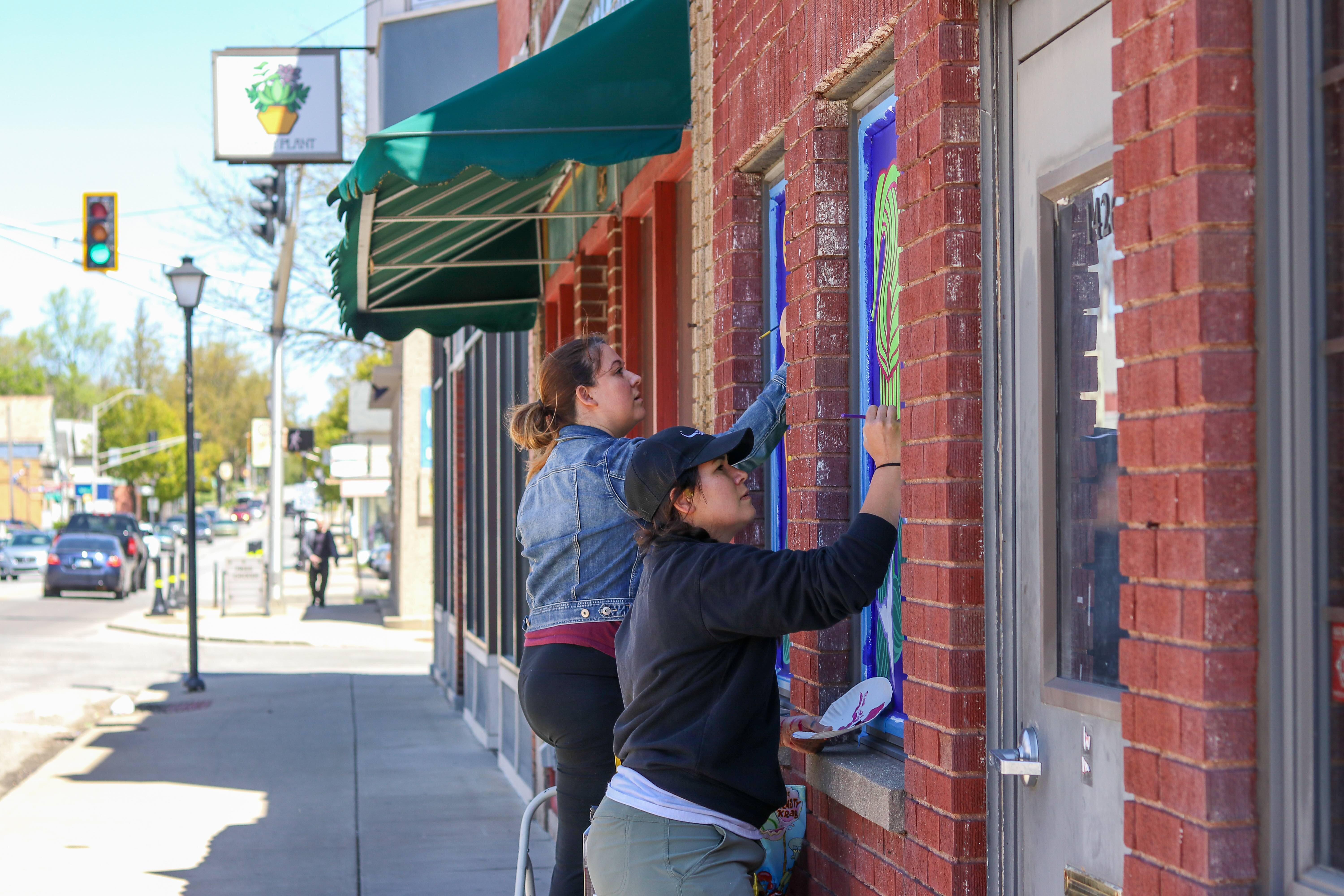 Sisters Cecilia Dunifon and Olivia Perez work on a "blooming" mural on Wells Street.